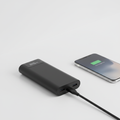 Sleek black portable power bank charging a smartphone on a clean surface